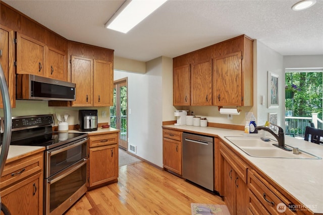 kitchen with visible vents, light countertops, a sink, light wood-style flooring, and stainless steel appliances