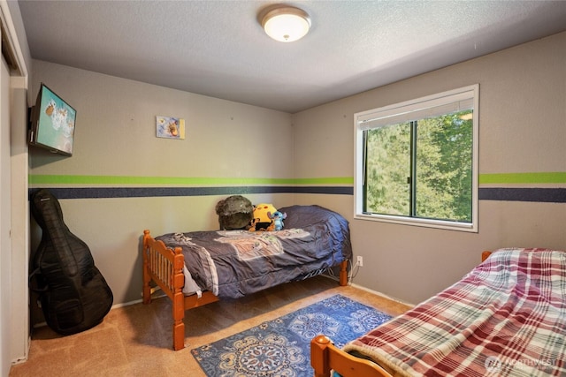 carpeted bedroom featuring a textured ceiling and baseboards