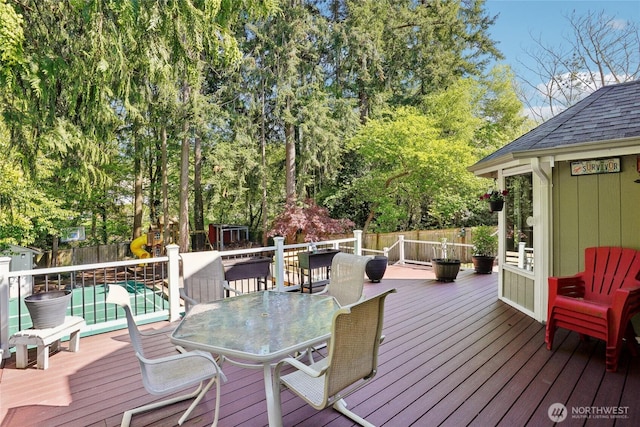 wooden deck with an outbuilding, outdoor dining area, a fenced backyard, and a shed