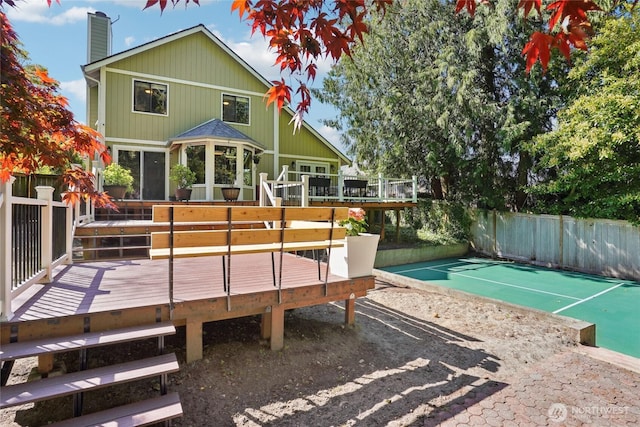 rear view of property featuring a deck, fence, and a chimney