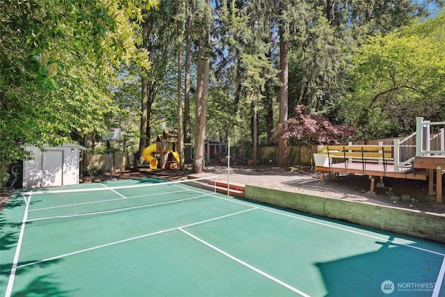 view of sport court with a playground, fence, an outbuilding, and a storage shed