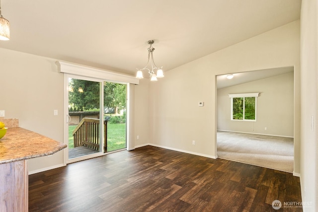 unfurnished dining area with lofted ceiling, dark wood-type flooring, baseboards, and a notable chandelier