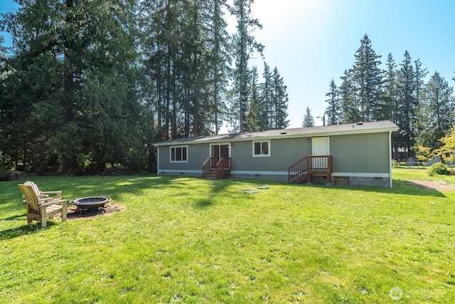rear view of property with a lawn, crawl space, and an outdoor fire pit