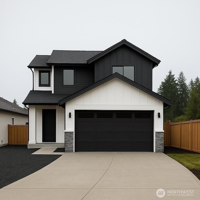 view of front facade with stone siding, concrete driveway, fence, and board and batten siding