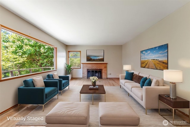 living area with baseboards, a fireplace, and light wood finished floors