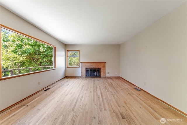 unfurnished living room with visible vents, baseboards, wood finished floors, and a fireplace