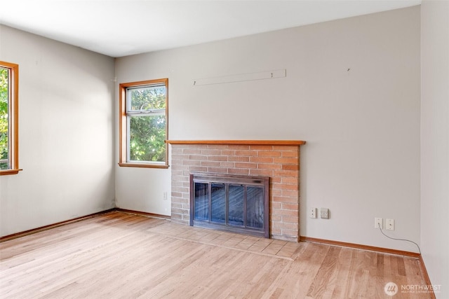 unfurnished living room featuring baseboards, wood finished floors, and a fireplace