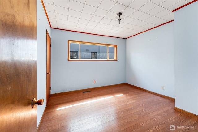 unfurnished room featuring baseboards, ornamental molding, wood finished floors, and visible vents