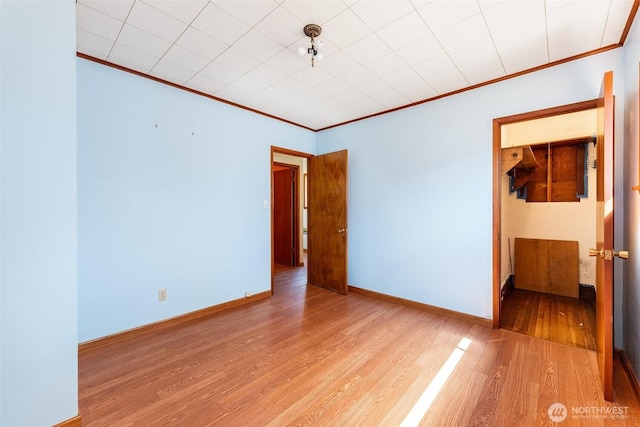 spare room with baseboards, ornamental molding, and wood finished floors