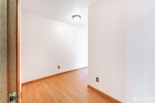 spare room with baseboards and light wood finished floors