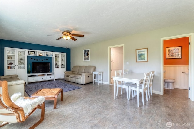 living room featuring a textured ceiling, a ceiling fan, and baseboards