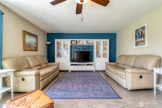 living area featuring a ceiling fan and a textured ceiling