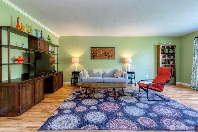 living room featuring baseboards, ornamental molding, light wood-style floors, and a textured ceiling