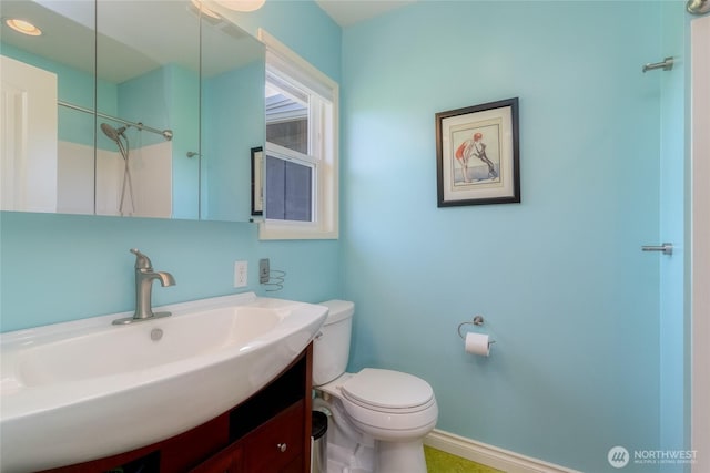 bathroom featuring toilet, vanity, and baseboards