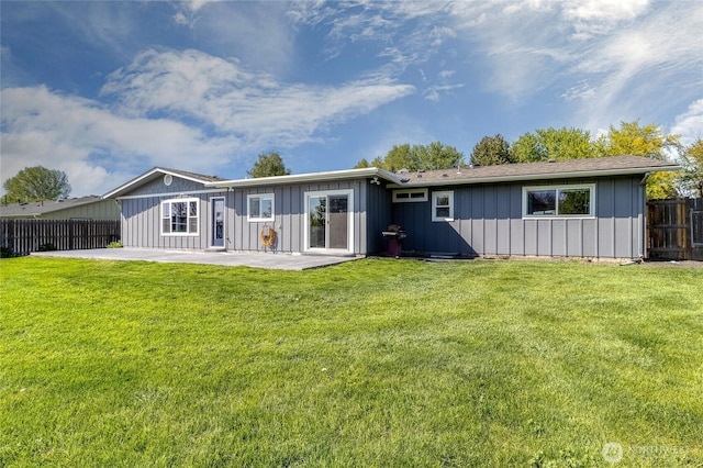 back of house with fence, board and batten siding, a lawn, and a patio