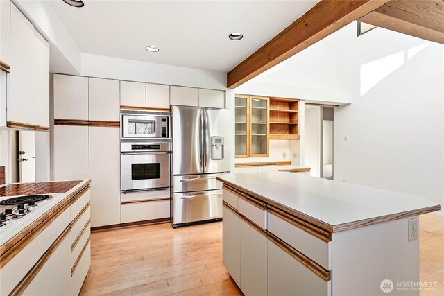 3884 Fort Bellingham Rd, Bellingham, WA 98225 - kitchen with a center island, light wood-style floors, stainless steel appliances, beamed ceiling, and white cabinetry