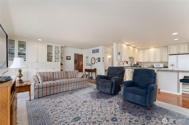 living area featuring visible vents, light wood-style floors, and recessed lighting