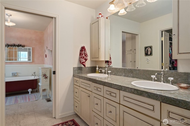full bath featuring a tub to relax in, double vanity, a sink, and a closet