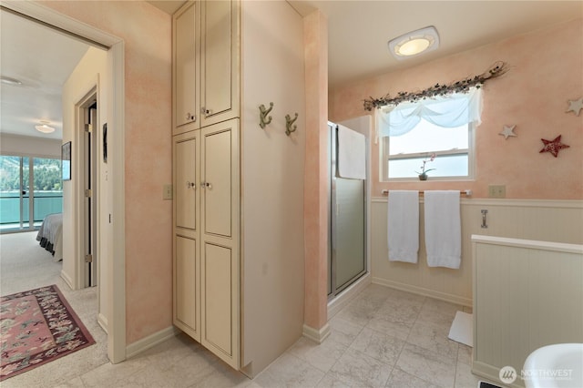 bathroom with wainscoting, a shower stall, marble finish floor, ensuite bathroom, and baseboards
