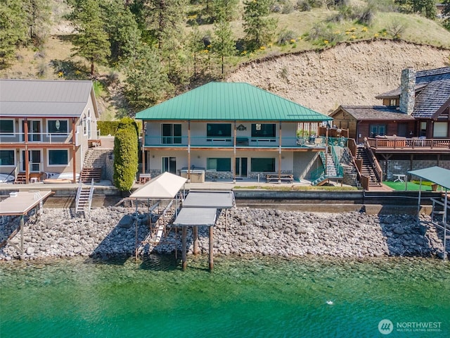 back of property featuring metal roof, a standing seam roof, a water view, and stairway
