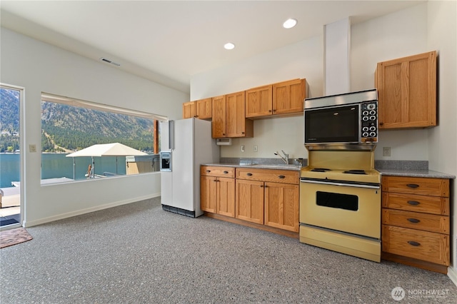 kitchen with white appliances, brown cabinetry, a sink, baseboards, and visible vents