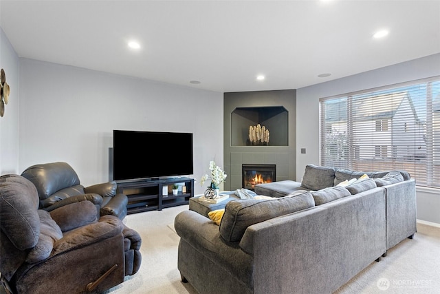 living area featuring recessed lighting, a glass covered fireplace, baseboards, and light colored carpet