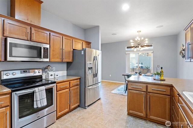 kitchen featuring decorative light fixtures, brown cabinets, appliances with stainless steel finishes, and a chandelier