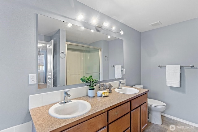 bathroom featuring toilet, a sink, double vanity, and a stall shower