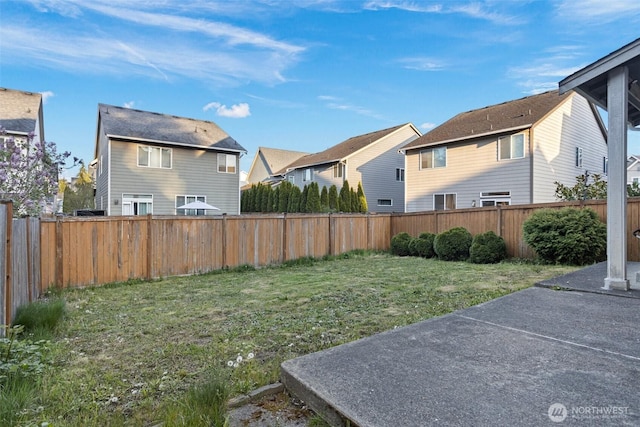 view of yard featuring a residential view, a patio area, and a fenced backyard