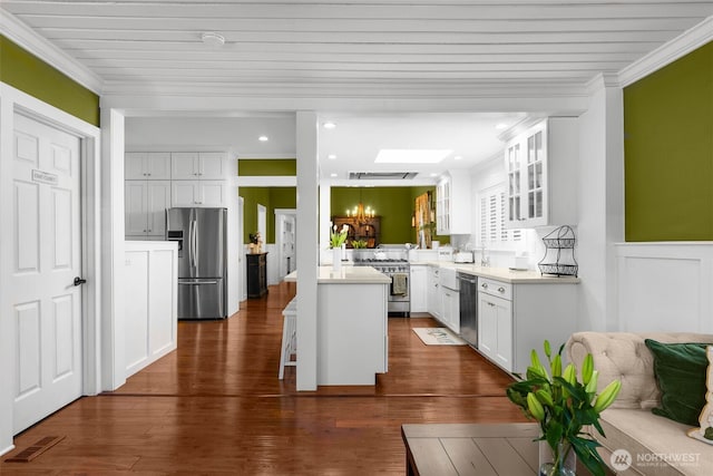 245 SE Bush St, Issaquah, WA 98027 - kitchen featuring appliances with stainless steel finishes, glass insert cabinets, crown molding, a kitchen bar, and white cabinetry