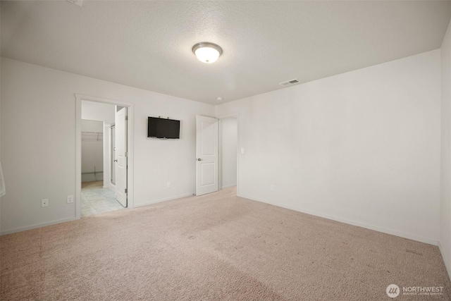 unfurnished bedroom with baseboards, ensuite bath, visible vents, and carpet floors