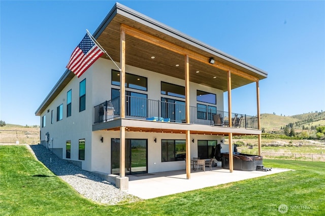 back of property with stucco siding, a patio, a balcony, and a hot tub