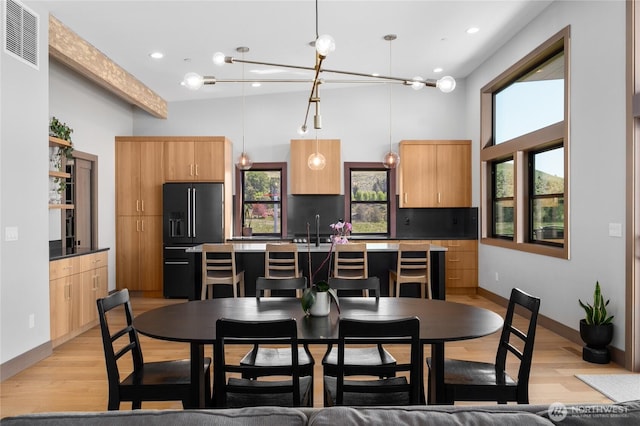 dining area with light wood finished floors, a towering ceiling, recessed lighting, and baseboards