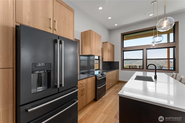 kitchen featuring black appliances, a sink, modern cabinets, light wood-style flooring, and recessed lighting