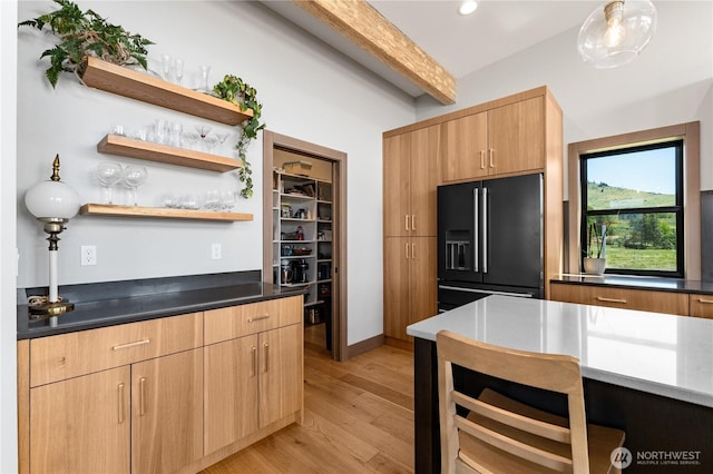 kitchen featuring high end black refrigerator, light wood-style flooring, open shelves, dark countertops, and beam ceiling