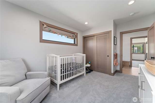 bedroom featuring multiple windows, a closet, recessed lighting, and light carpet