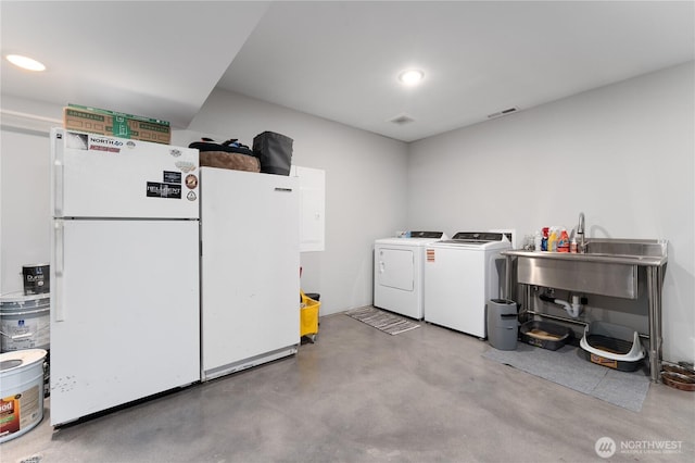 clothes washing area with a sink, washing machine and dryer, and recessed lighting
