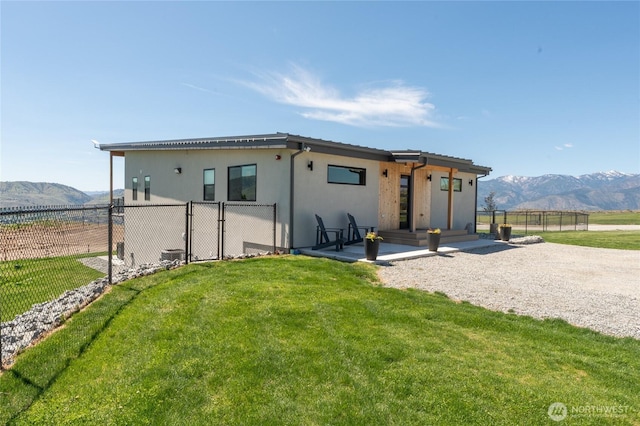 ranch-style house with a mountain view, stucco siding, a gate, and a patio