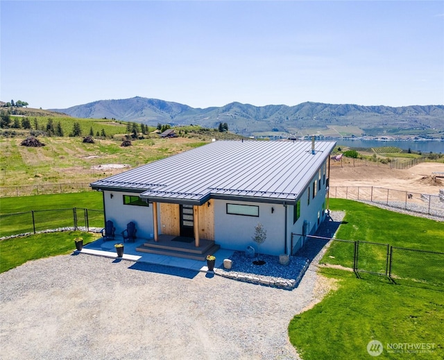 view of front facade with a standing seam roof, metal roof, stucco siding, and a gate