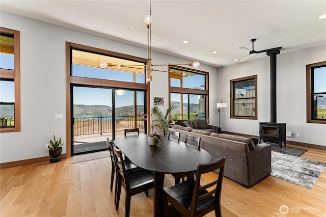 dining space featuring a wood stove, light wood-style floors, recessed lighting, and baseboards