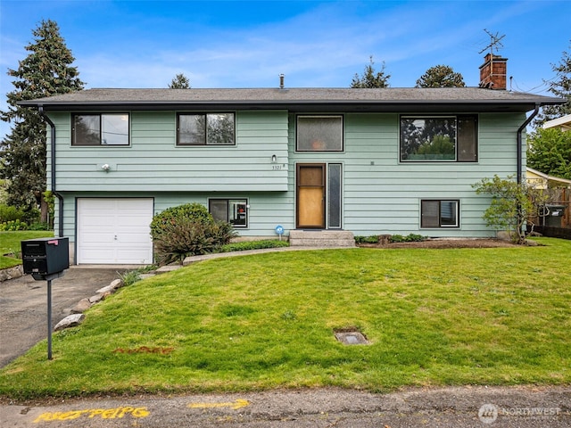 raised ranch featuring an attached garage, a chimney, driveway, and a front yard