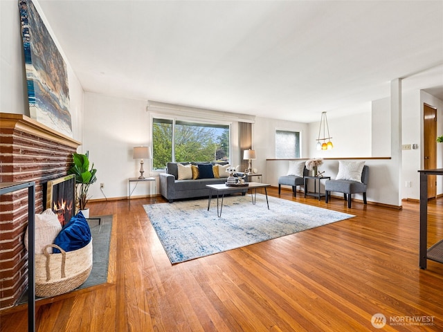 living area with baseboards, plenty of natural light, wood finished floors, and a fireplace
