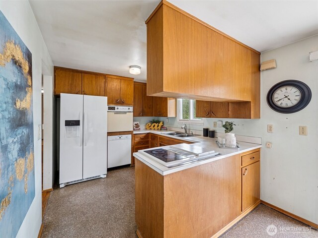 kitchen featuring brown cabinets, a sink, light countertops, a peninsula, and white appliances