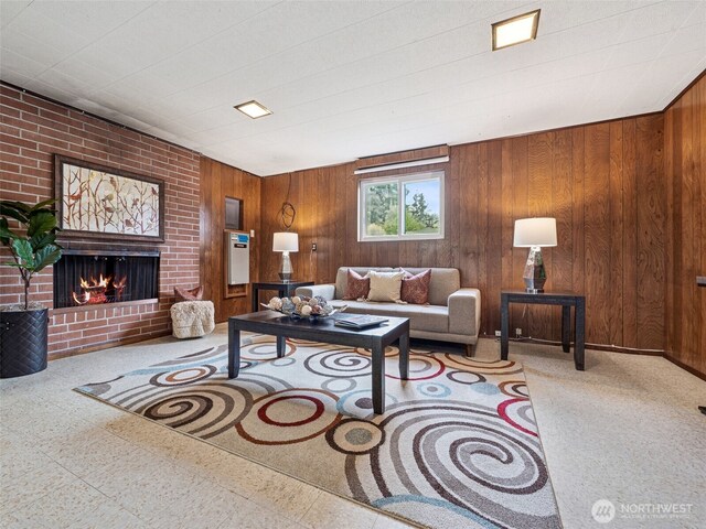 living room with wooden walls, tile patterned floors, and a brick fireplace