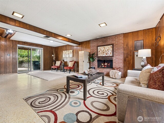 living room featuring wood walls, visible vents, and a fireplace