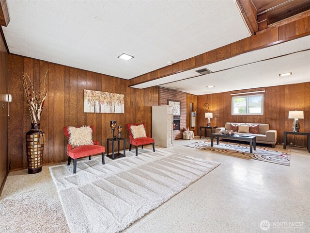 living area with wooden walls, tile patterned floors, and a fireplace