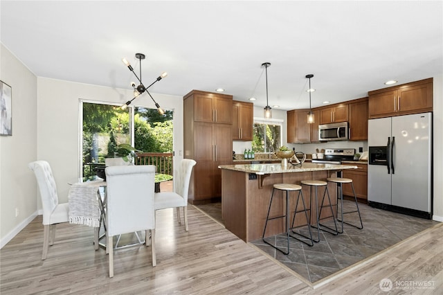 2524 171st St SE, Bothell, WA 98012 - kitchen with stainless steel appliances, light wood-type flooring, a center island, a breakfast bar, and recessed lighting