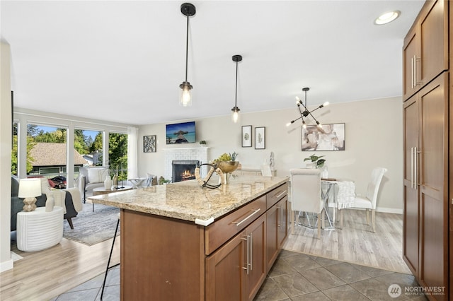2524 171st St SE, Bothell, WA 98012 - kitchen featuring open floor plan, a brick fireplace, a breakfast bar, a center island, and light stone countertops
