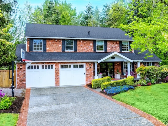 traditional-style house featuring covered porch, driveway, brick siding, a front lawn, and an attached garage
