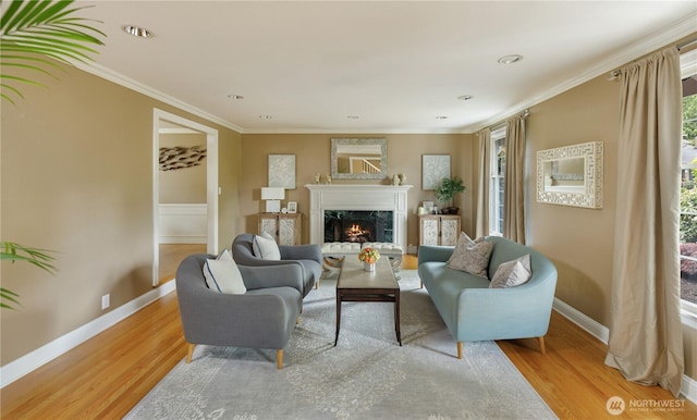 living area featuring a high end fireplace, baseboards, ornamental molding, and light wood-style flooring